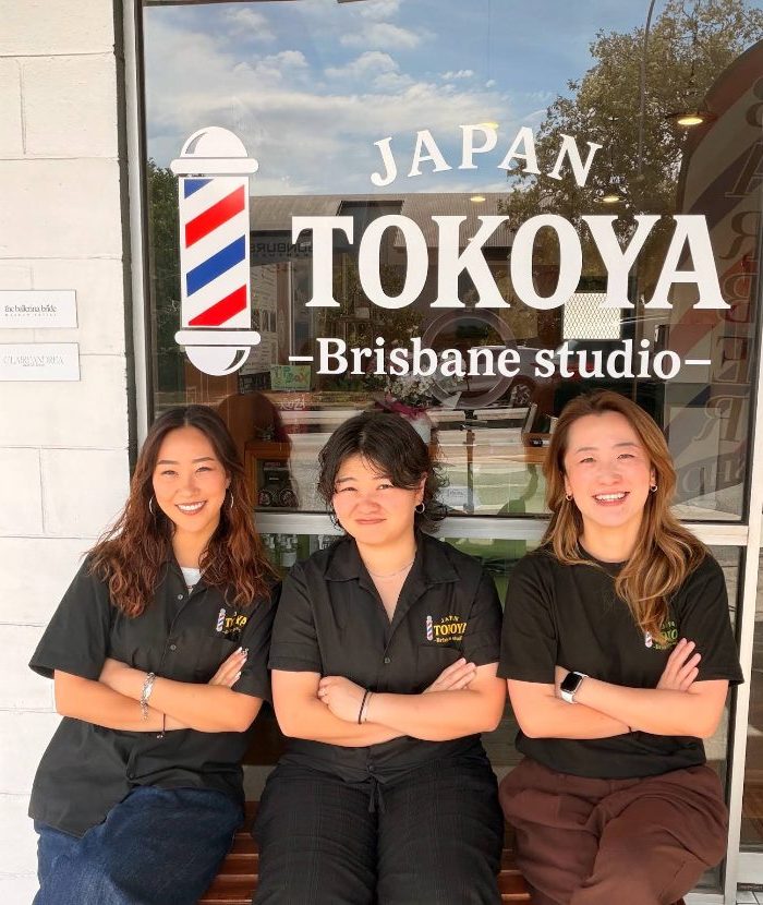 Three Tokoya barbers in black shirts sitting under the Tokoya Japan window sign.